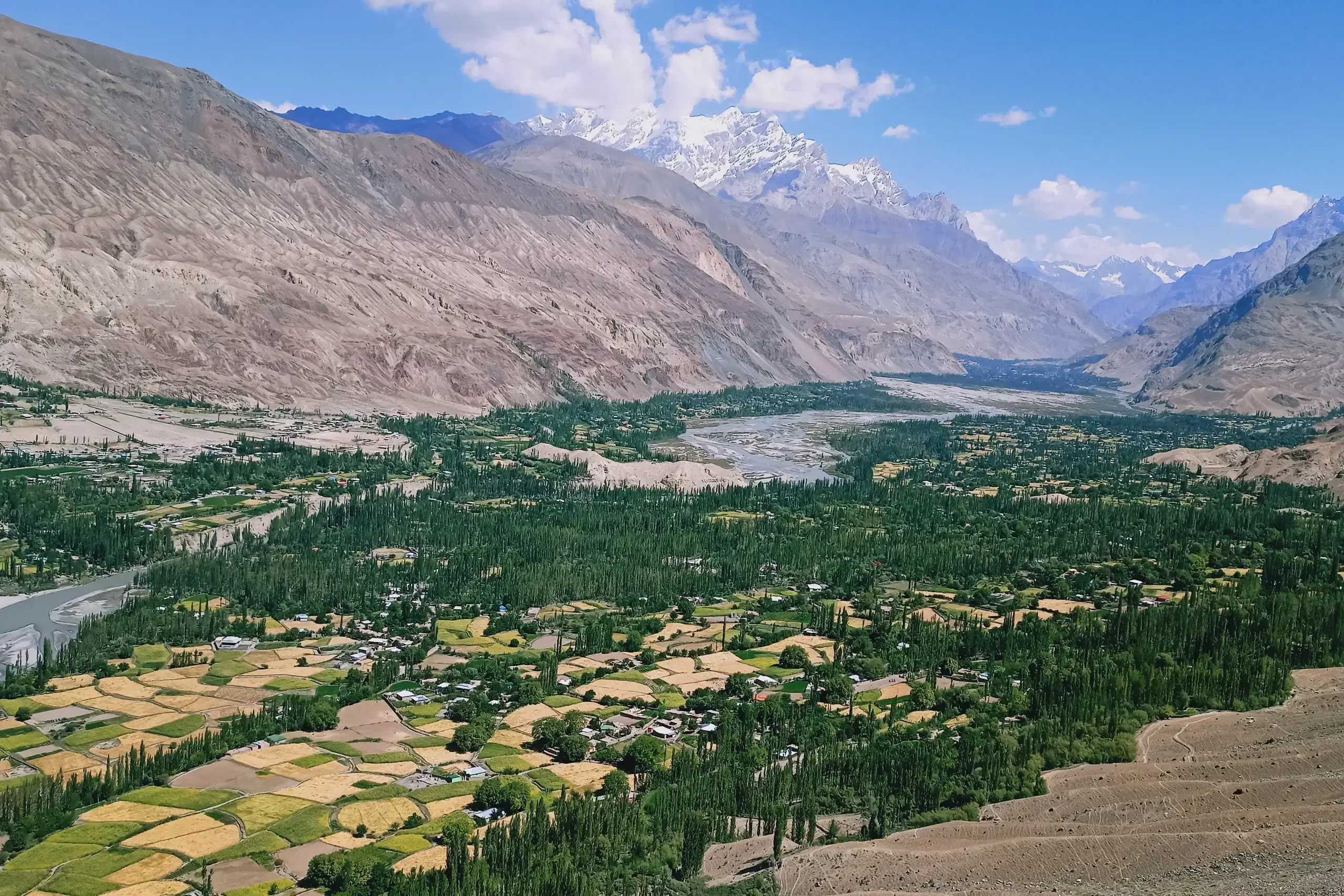 A wide valley of terraced fields and settlements between mountain ranges in northern Pakistan.