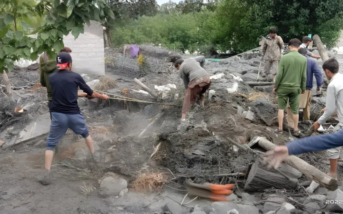 People shovelling rock and silt debris from land in northern Pakistan.